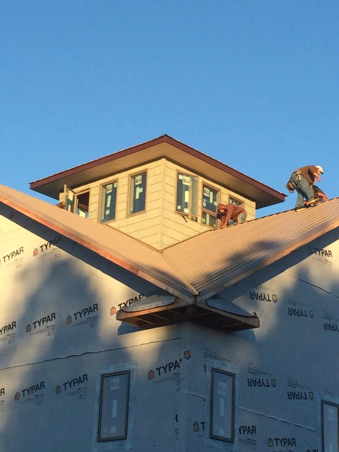 Roofers working around a rooftop cupola on a new metal roof at sunset — Roof Waterproofing in Wilton by Roofing Brothers